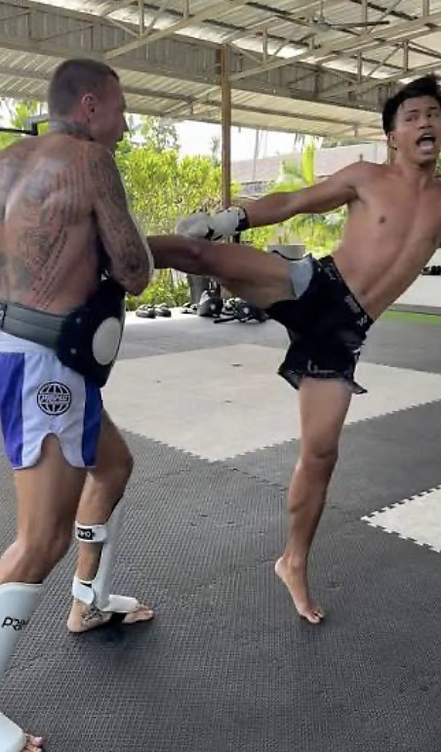 A fighter landing a body kick on the pads