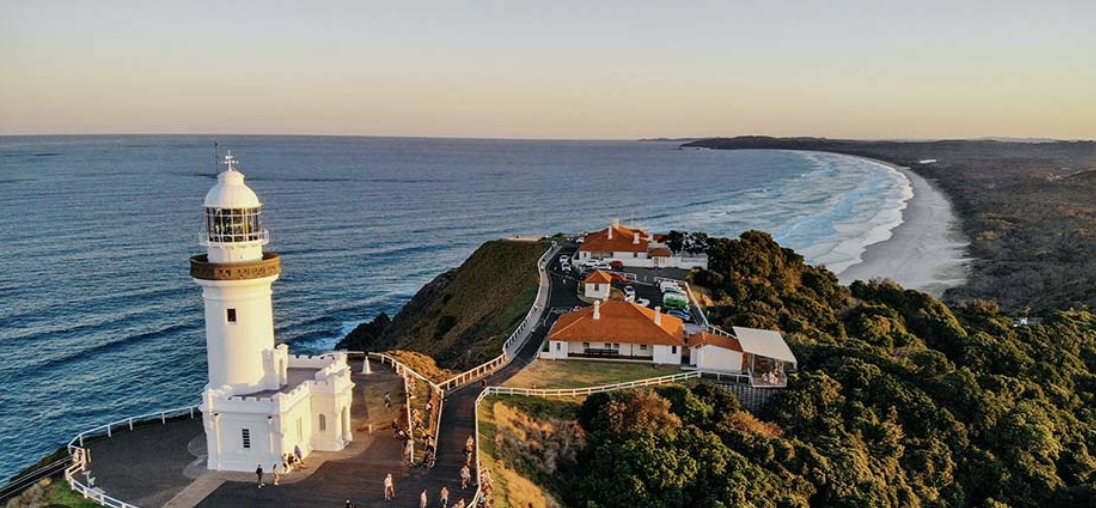 Cape Byron lighthouse at golden hour, with the beach curving away below
