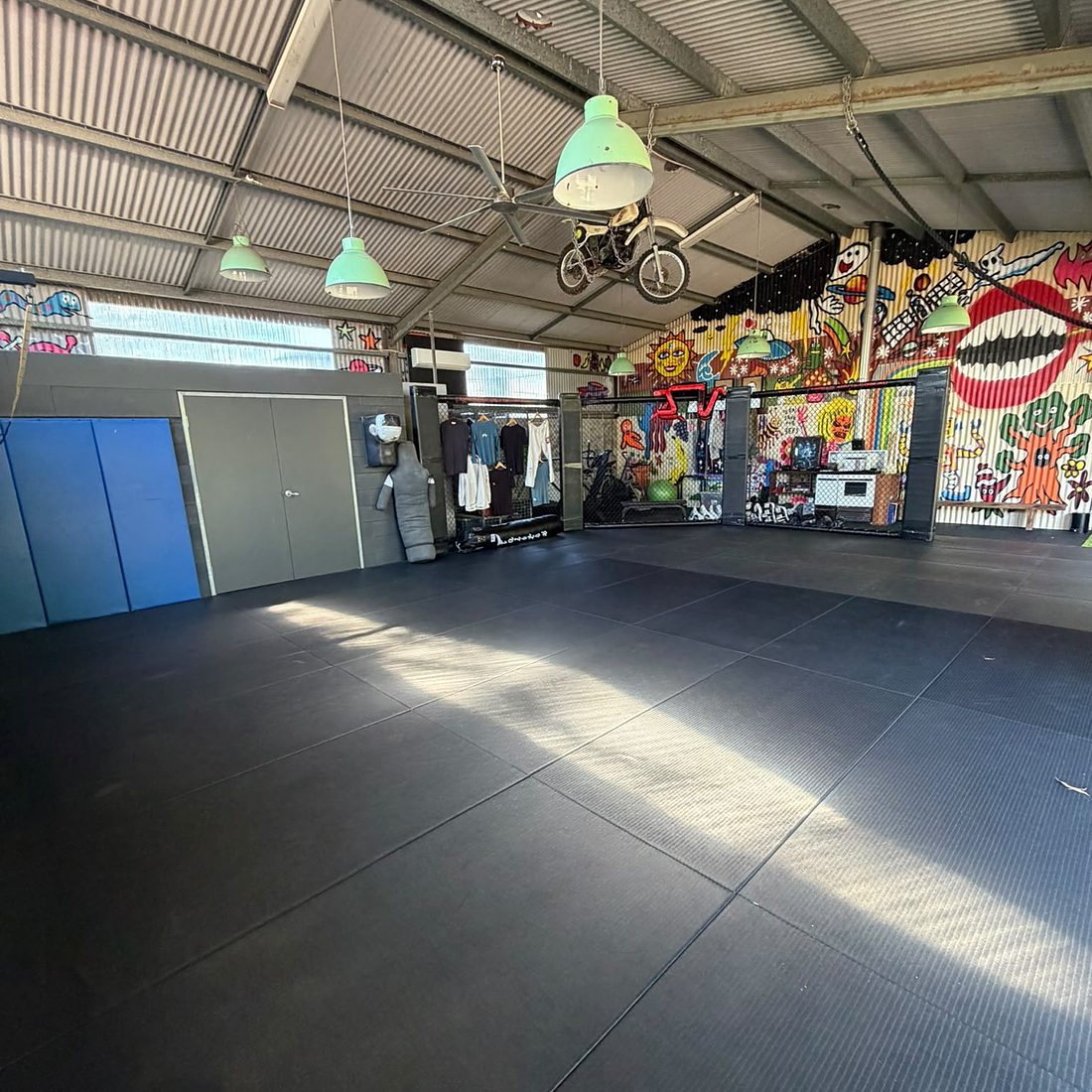 The matted floor of the training shed, murals at the far end