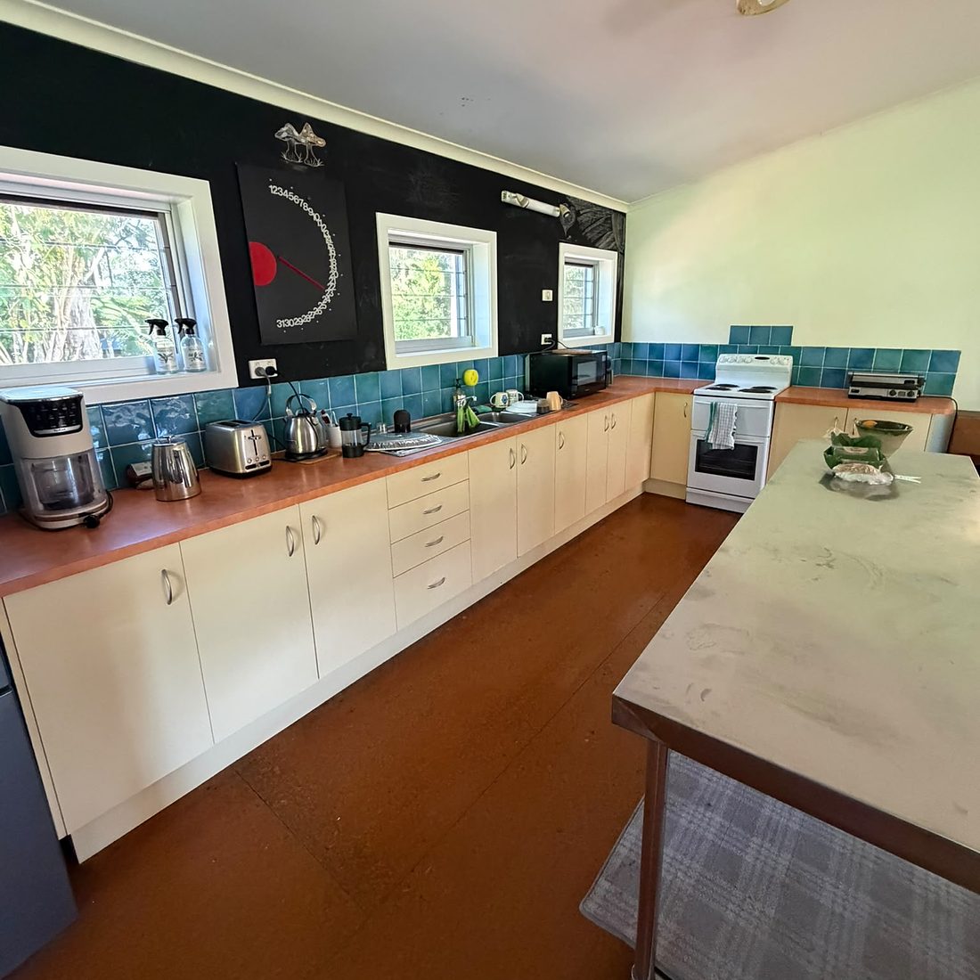 The camp-house kitchen — long bench, stove, stainless prep table